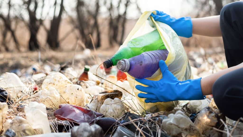 man collecting scattered plastic bottles from the ground